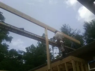 Carpenter setting a ridge beam over a new addition frame — Ice Dam Removal by Roofing Brothers in Netawaka