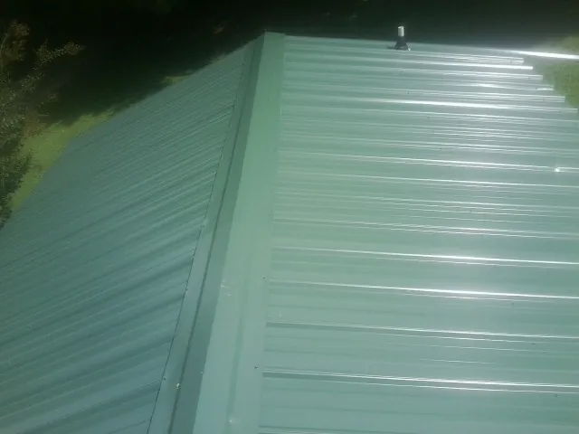 New green metal panels meeting at the ridge of a roof — Flat Roof Repair work by our crew in Netawaka