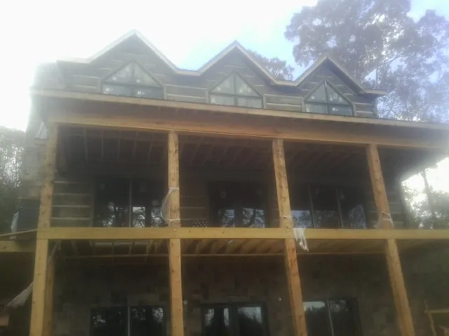 Dormers and porch framing on a large log home under construction — Roof Coating work by our crew in Netawaka