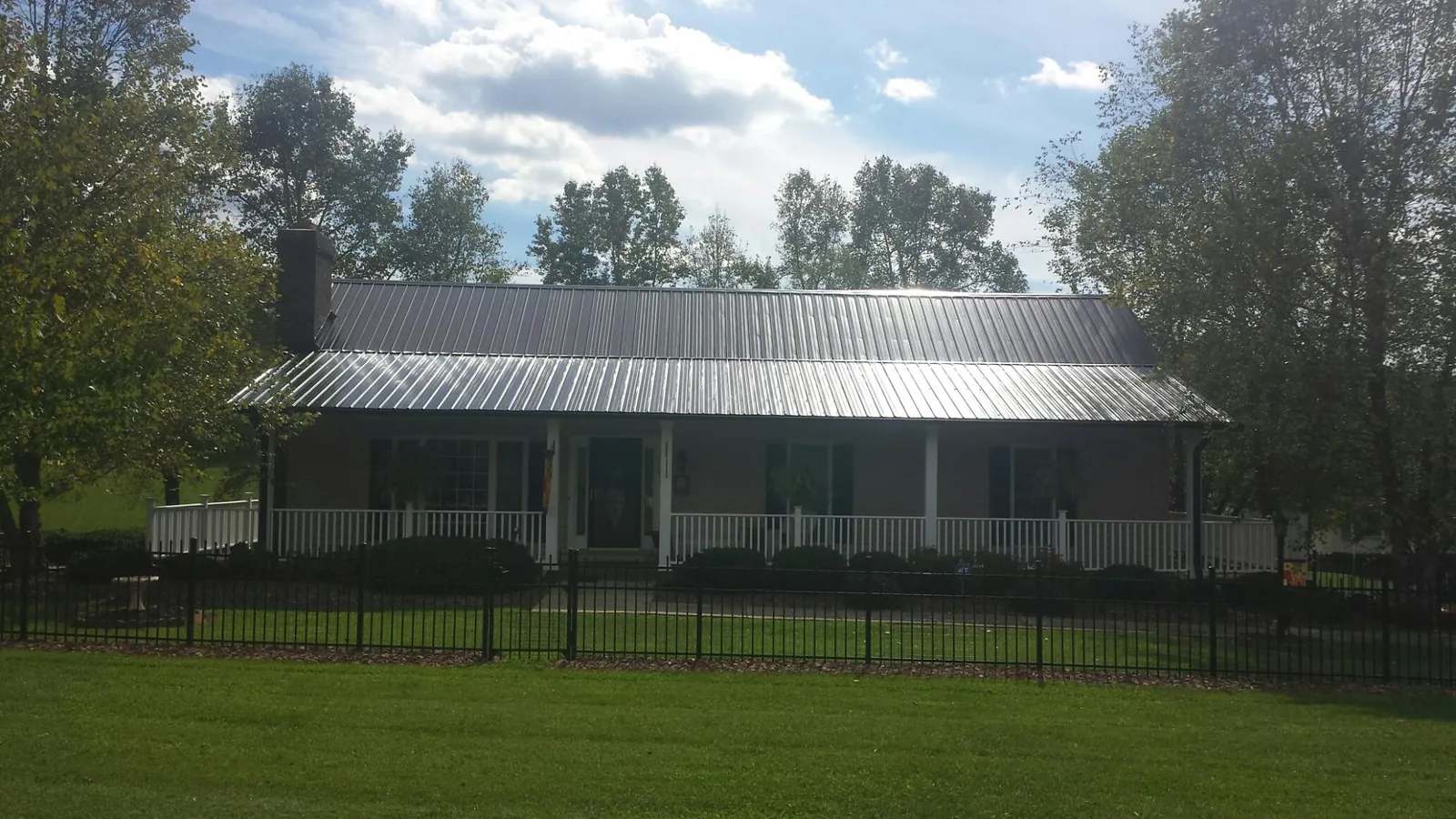 Gray metal roof on a brick ranch with a full width front porch — Gutter Guard Installation work by our crew in Netawaka