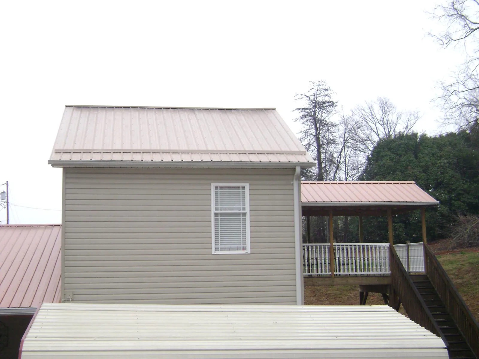 Tan metal roofs on a two story addition and attached porch, from a Roof Replacement job in Netawaka