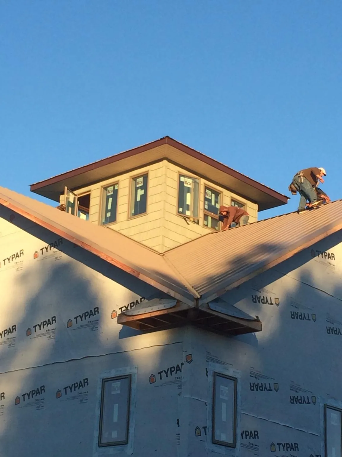 Roofers working around a rooftop cupola on a new metal roof at sunset — Roof Waterproofing in Netawaka by Roofing Brothers